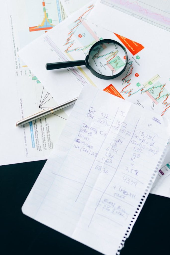 Financial documents and charts with a magnifying glass, symbolizing analysis and data review.