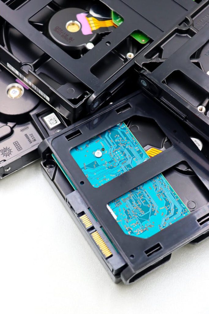 Close-up of multiple black internal hard drives stacked on a white surface showcasing circuit boards.